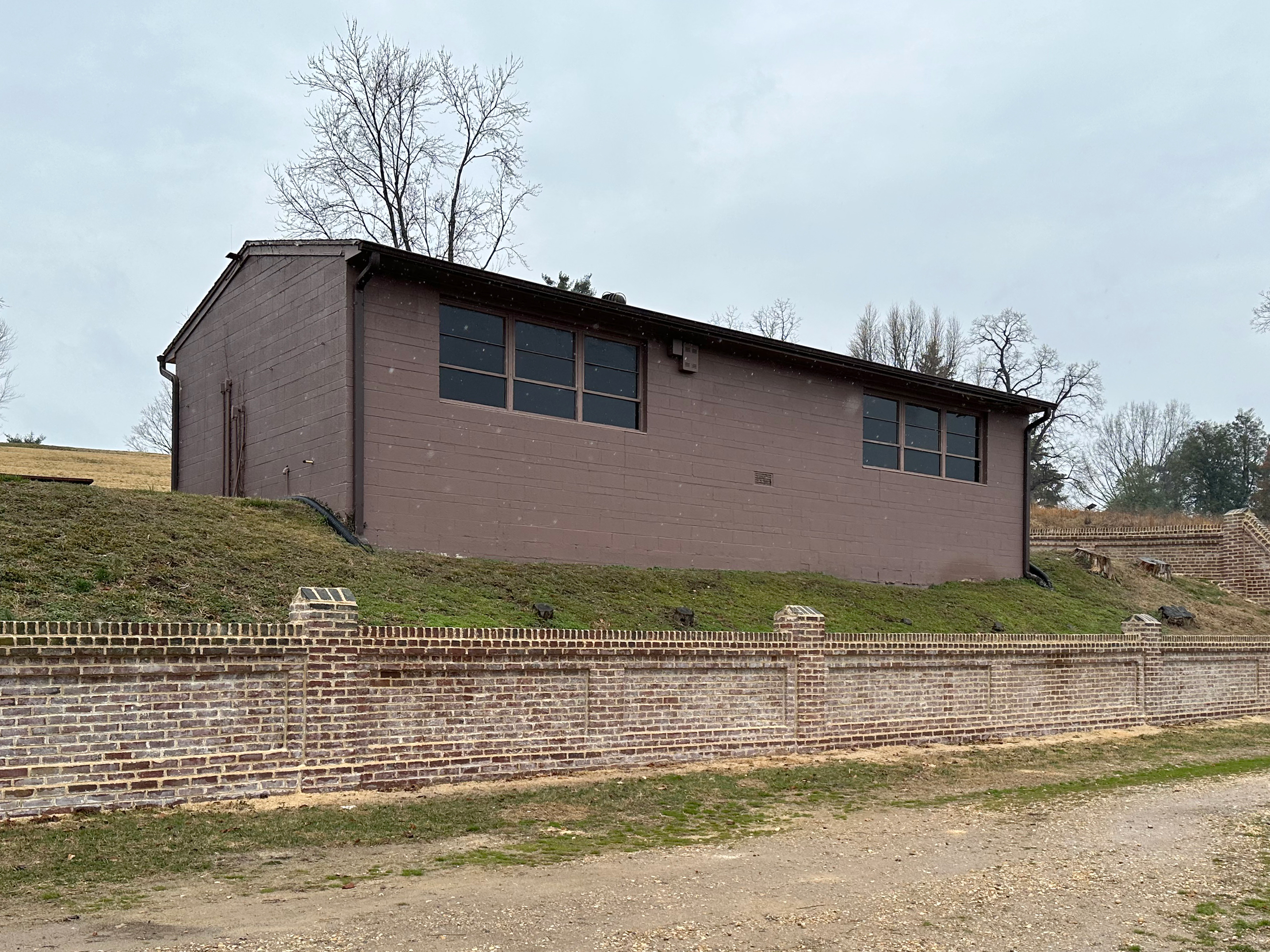 Concrete Structure Near Fredericksburg National Cemetery A rectangular concrete structure painted brown on the side of a hill near a stone wall.