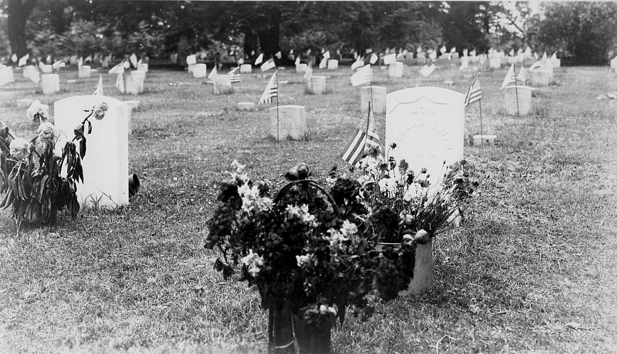 Black and white photo of graves in national cemetery with flowers in front