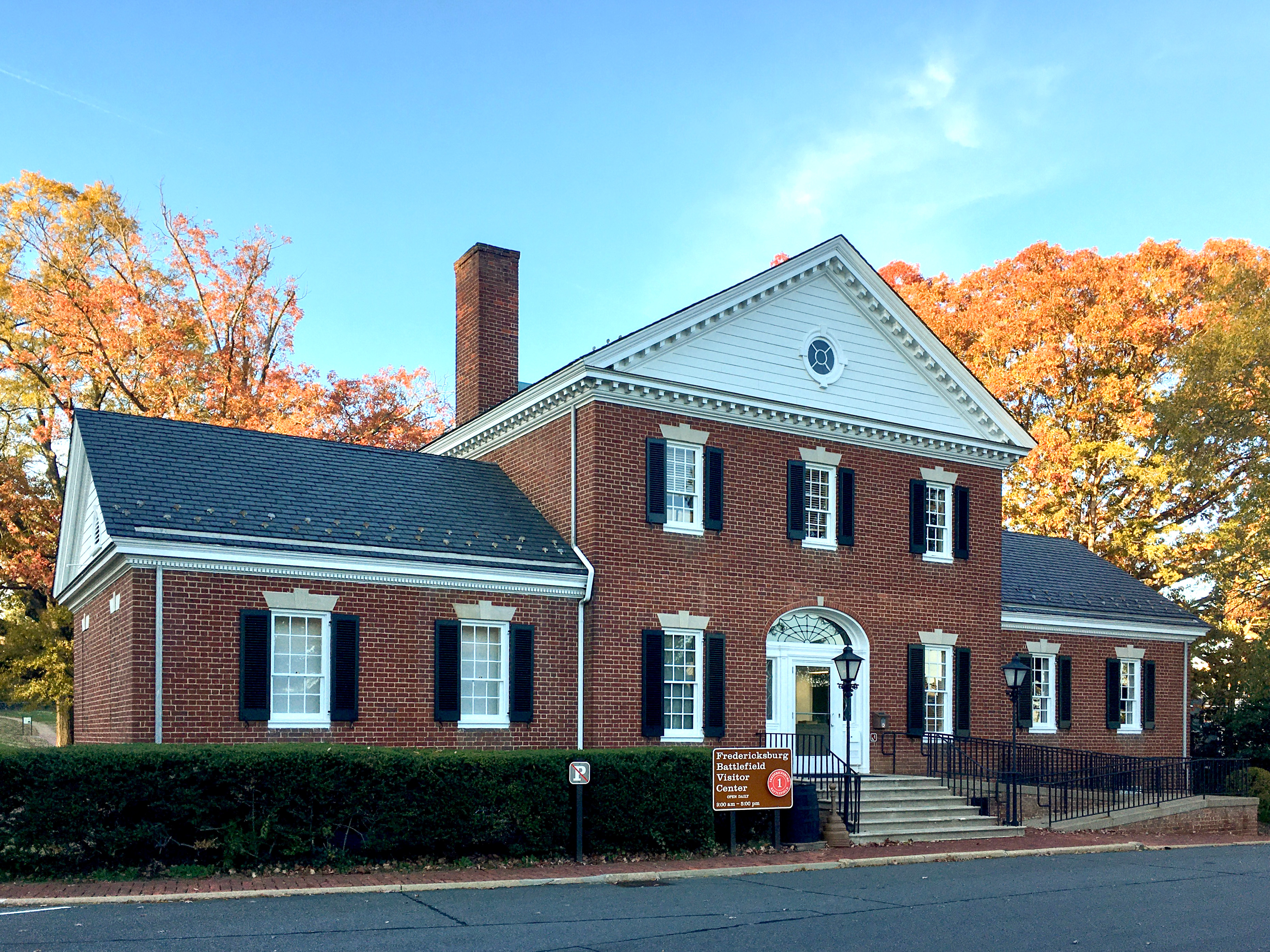 Fredericksburg Battlefield Visitor Center Front in Fall A two story brick building with stairs and ramp entrance.
