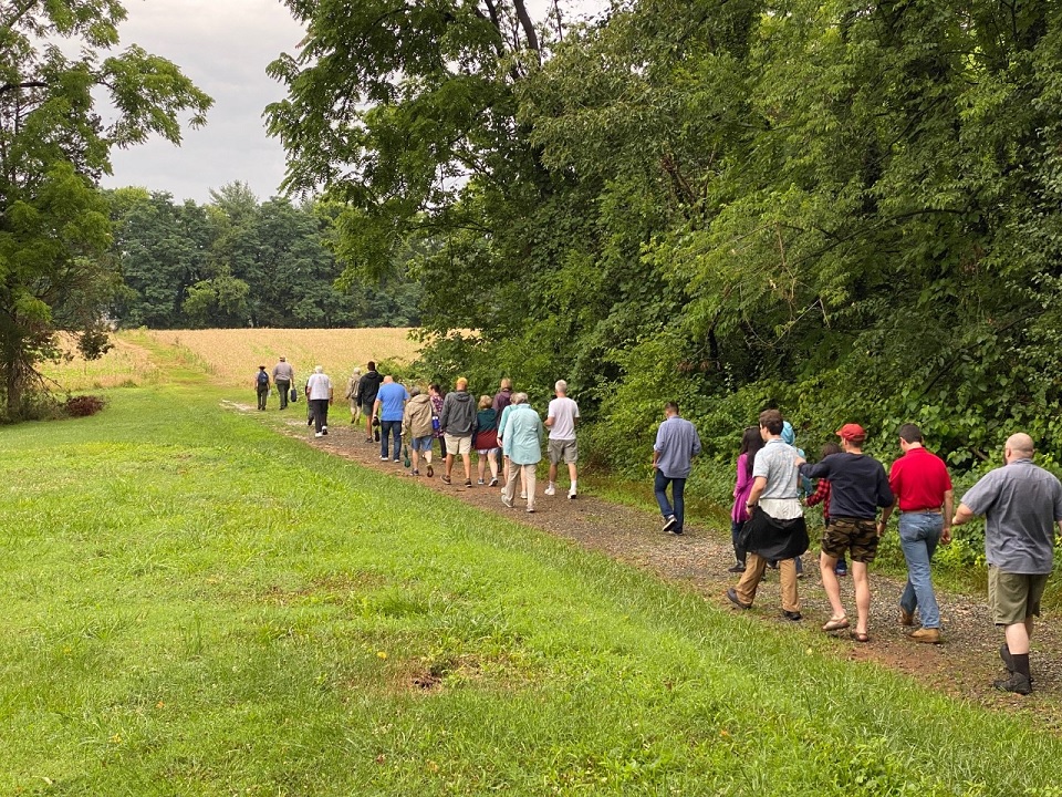 Group of Visitors following two park rangers along a path through a farm field