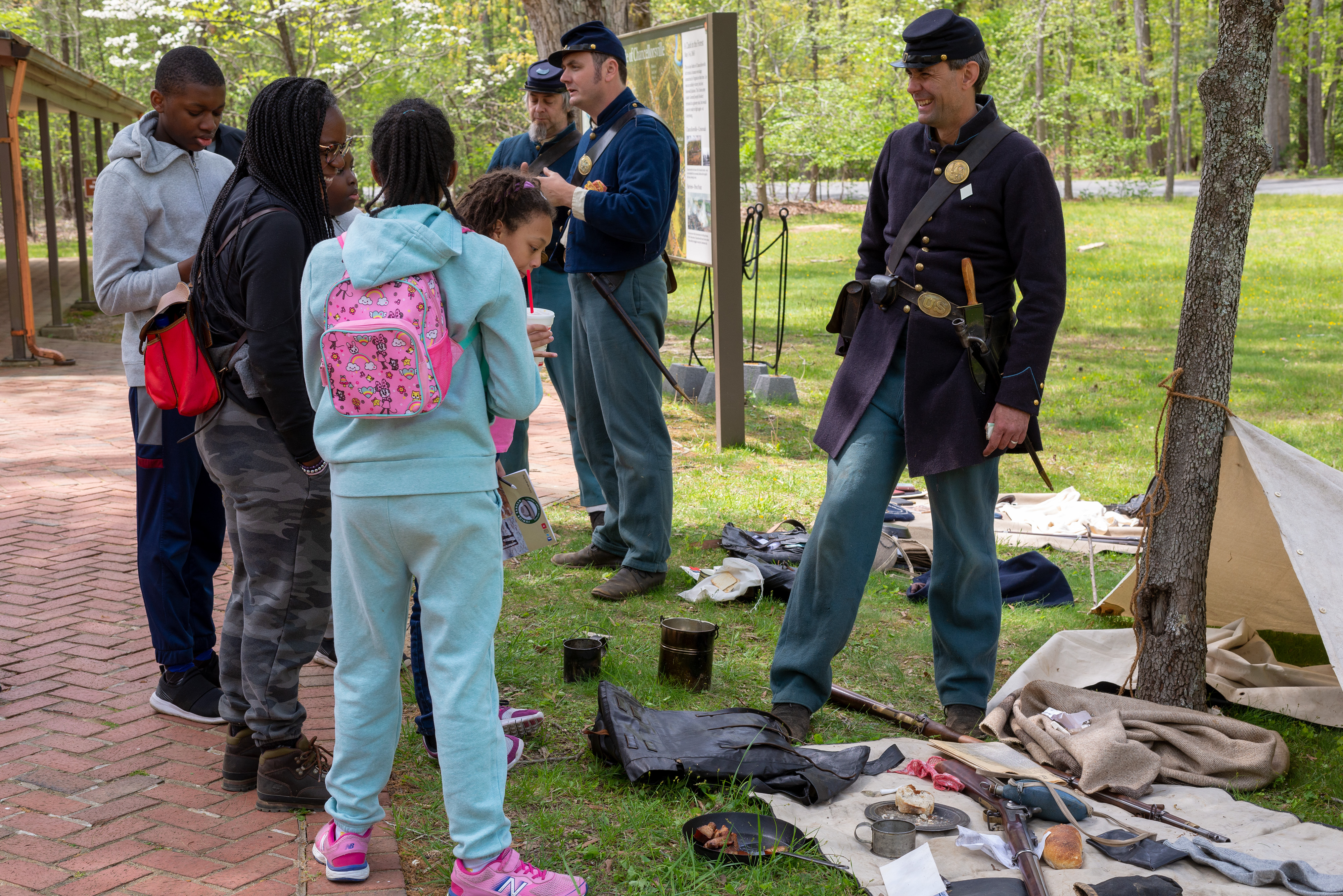 Living Historians at Chancellorsville 2022 Living historians, Union soldiers, talk to a family outside.