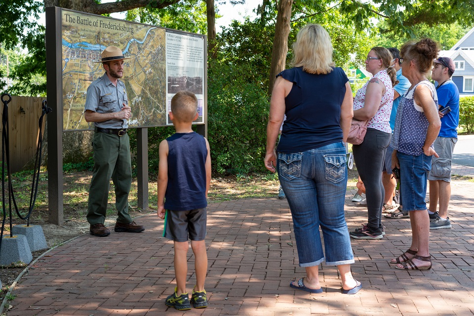 SunkenRoadTourWithRanger Ranger conducting tour with group of visitors in front of a painting depicting the Battle of Fredericksburg