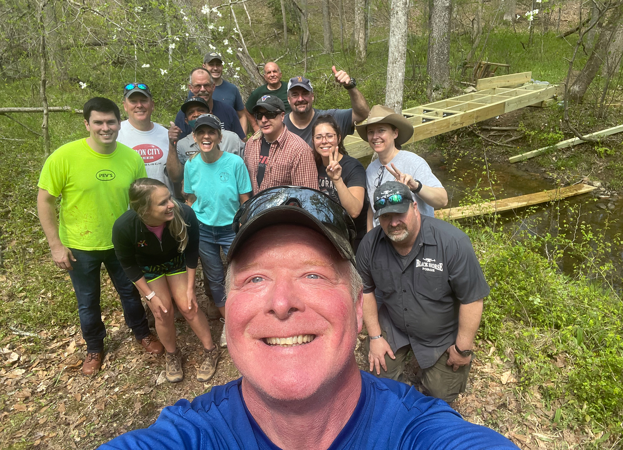 Maintenance Volunteers at FRSP A man takes a selfie with a group of adult volunteers after completing a wooden footbridge.