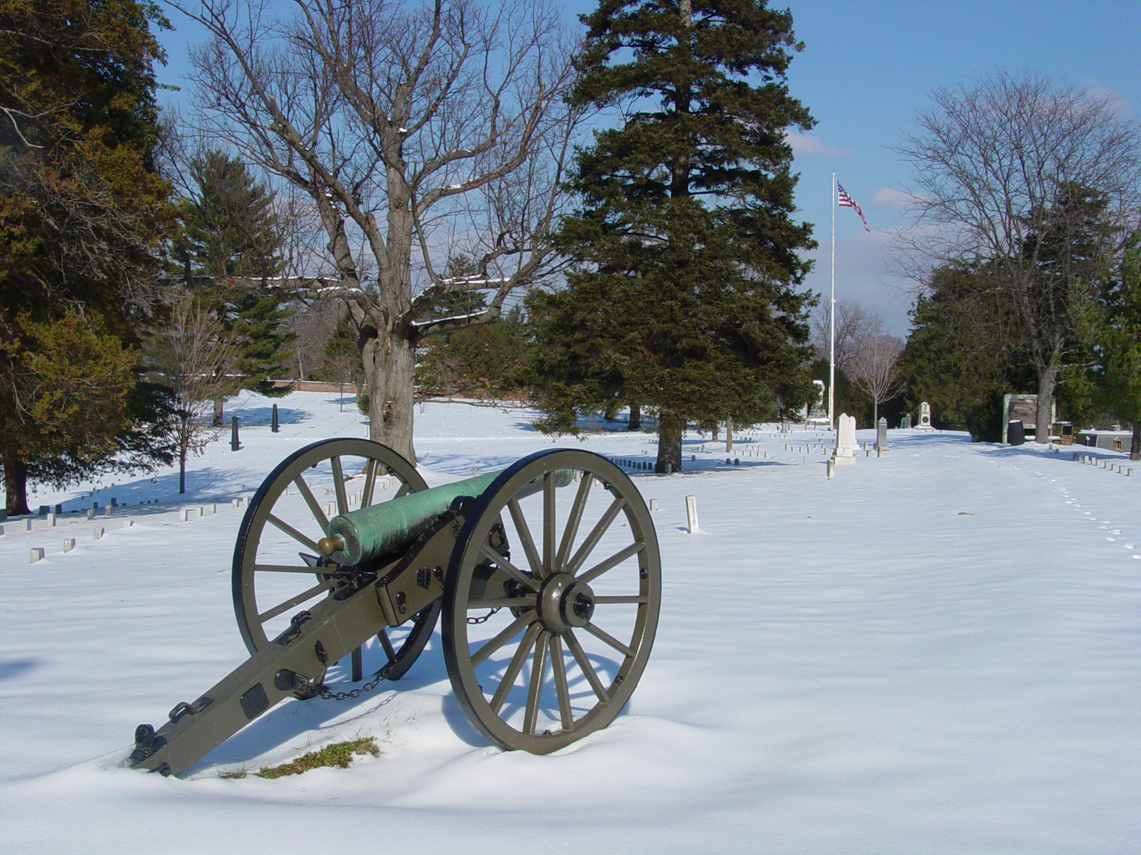 Cannon in cemetery covered in snow.