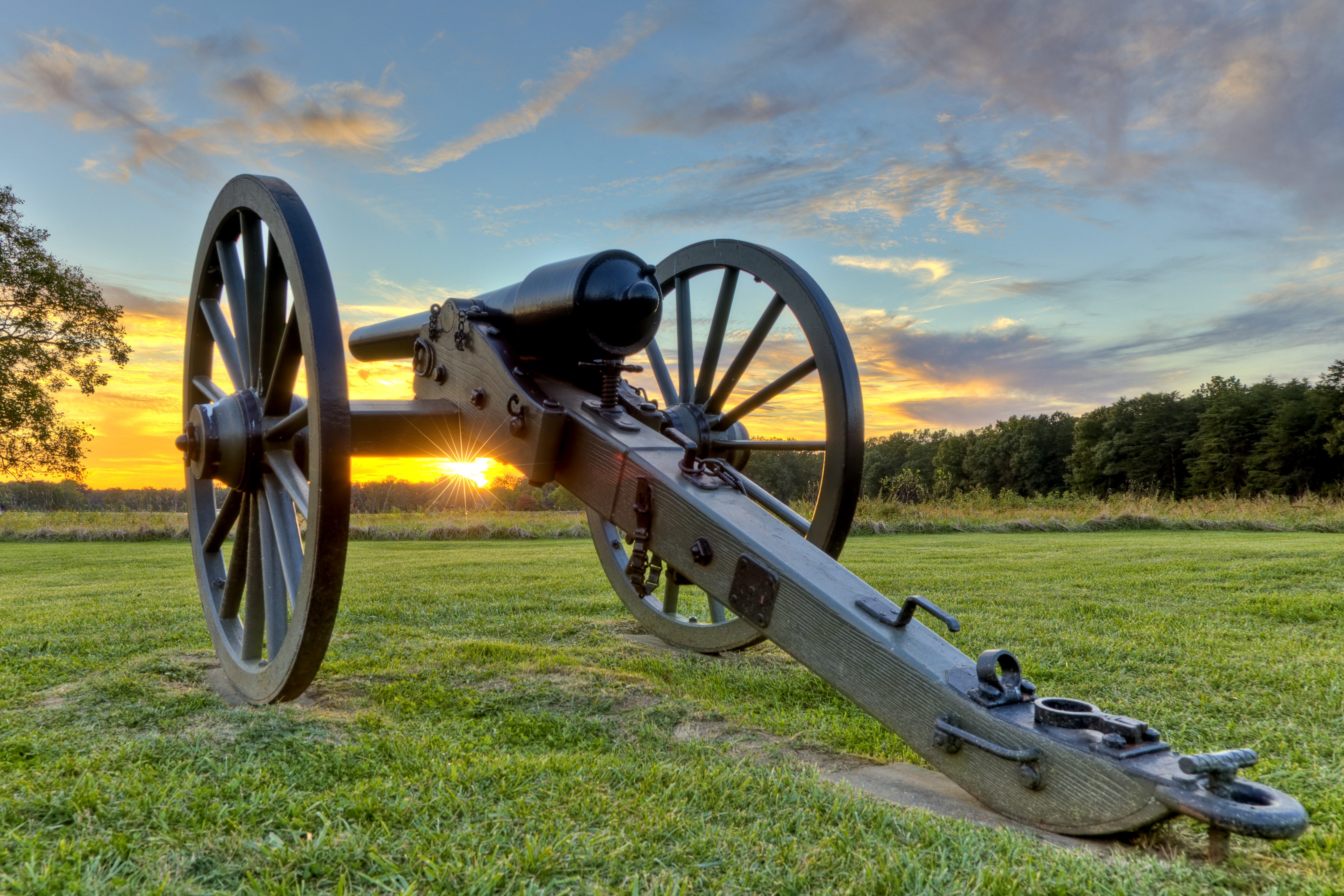 A cannon in a field at sunset