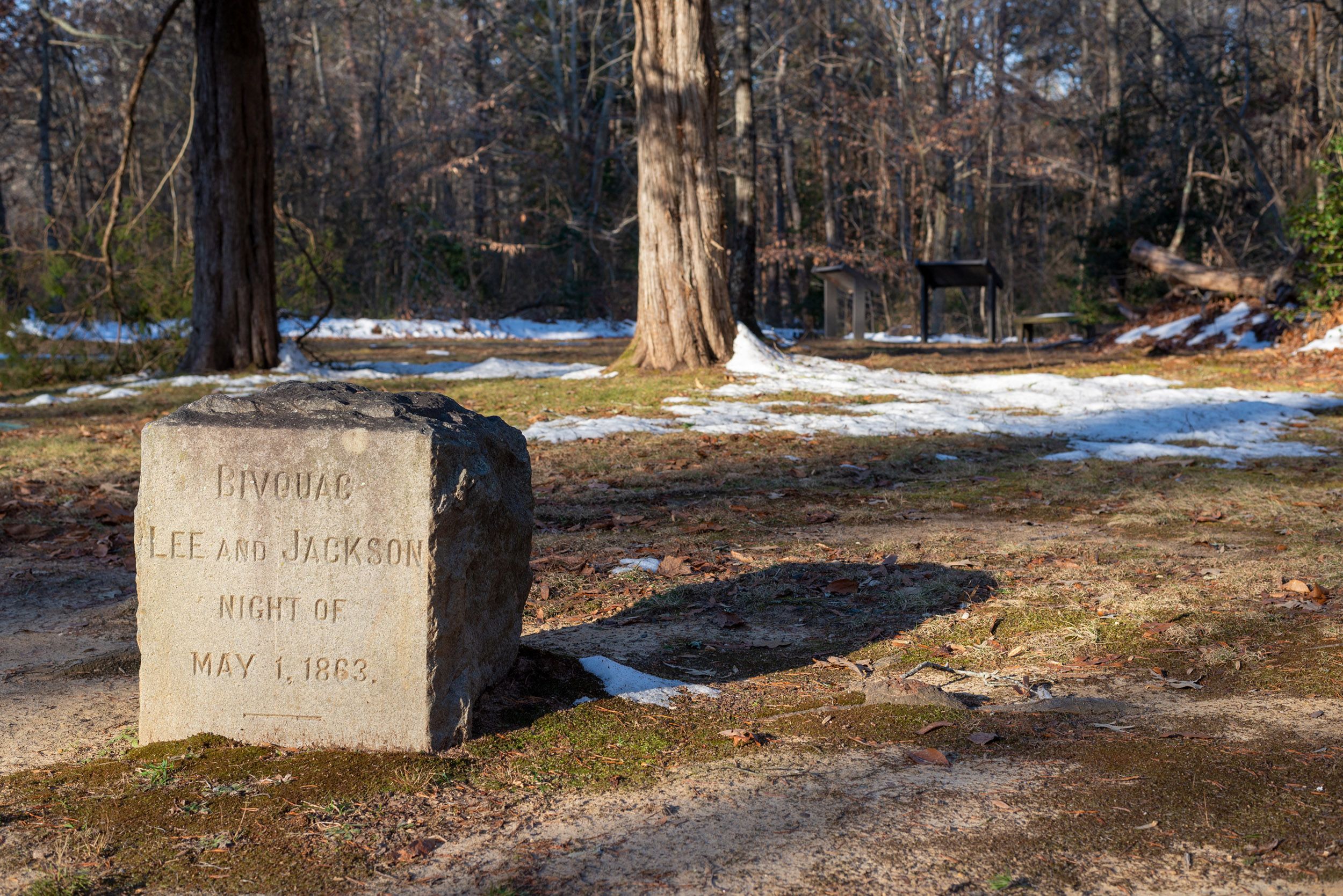 A stone marker in an open space with some snow on the ground.