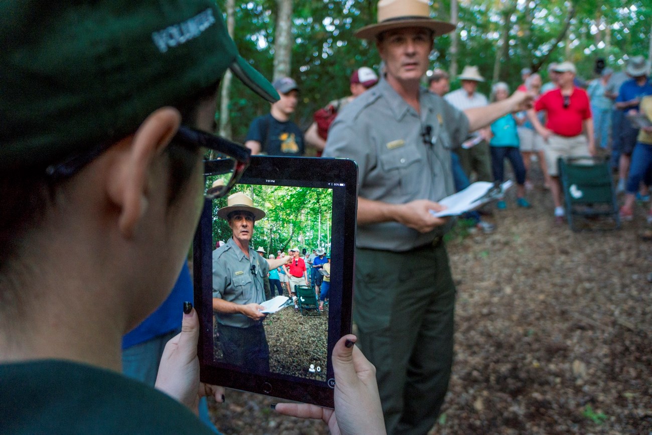 Intern holds iPad as park ranger giving program appears on screen