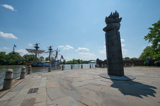 Kalmar Nyckel sails by the monument at Fort Christina NHL