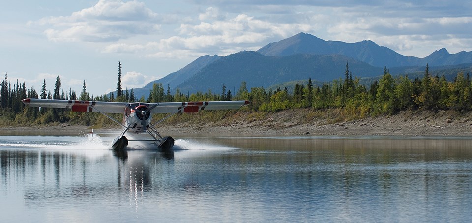 A floatplane lands on a lake in front of a distant mountain A floatplane lands on a lake in front of a distant mountain
