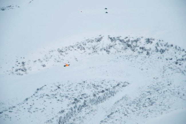 An aerial view of snowmachines on the arctic tundra in winter