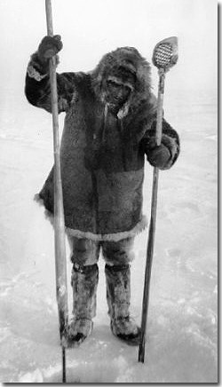 Coastal Eskimo ice fisherman wearing caribou skin parka, pants, and boots