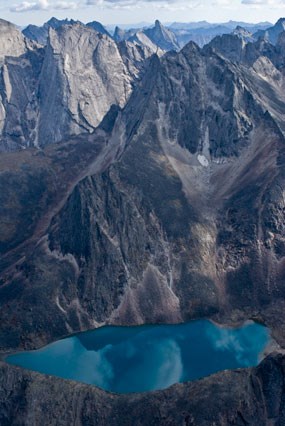 The grey granite spires of the Arrigetch Peaks frame a turquoise blue cirque lake. The grey granite spires of the Arrigetch Peaks frame a turquoise blue cirque lake.