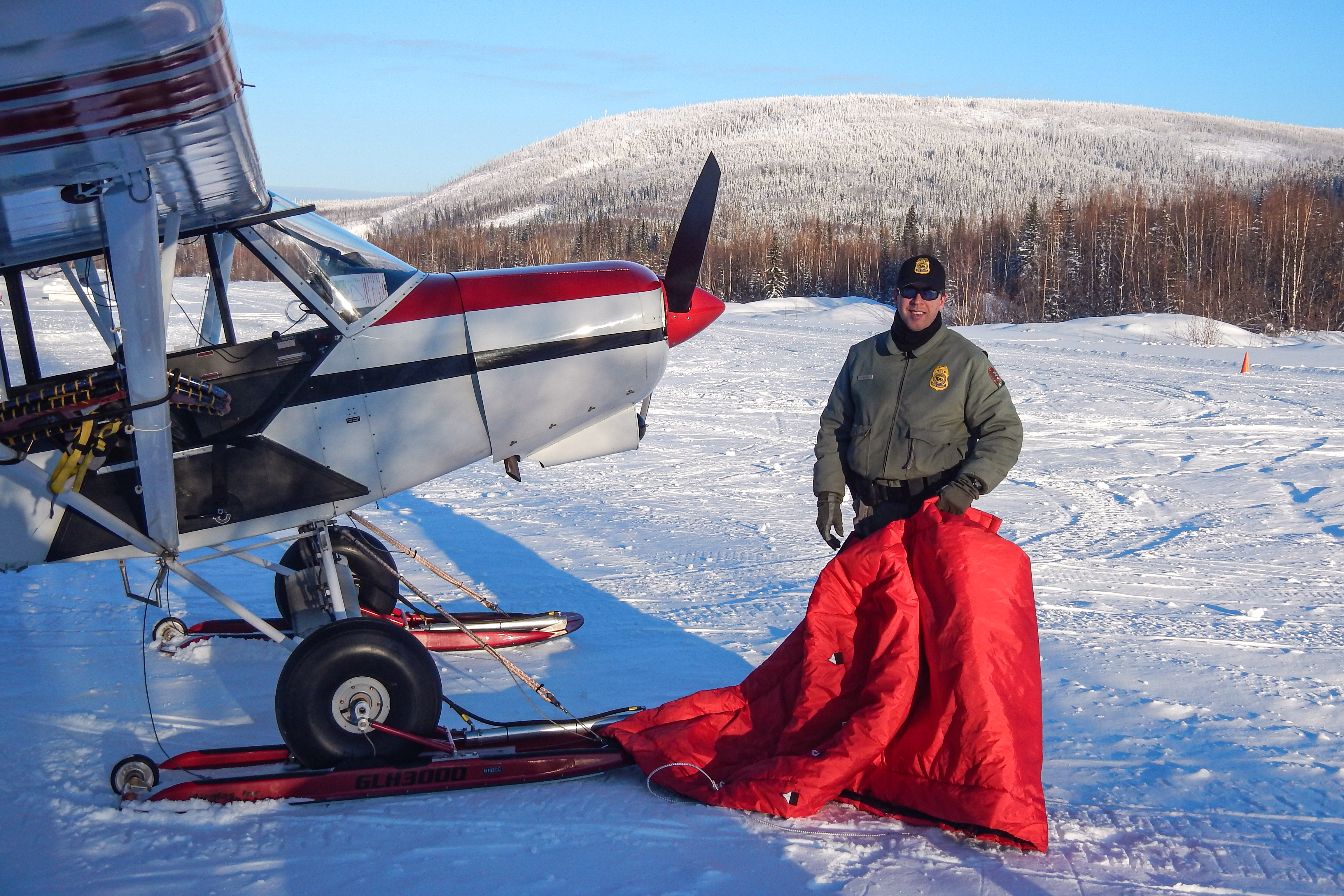 Chief Ranger/Pilot Scott Sample with a Top Cub bushplane on wheel-skis at the Coal Creek Airstrip in Yukon-Charley Rivers National Preserve in winter. Chief Ranger/Pilot Scott Sample with a Top Cub bushplane on wheel-skis at the Coal Creek Airstrip in Yukon-Charley Rivers National Preserve in winter.