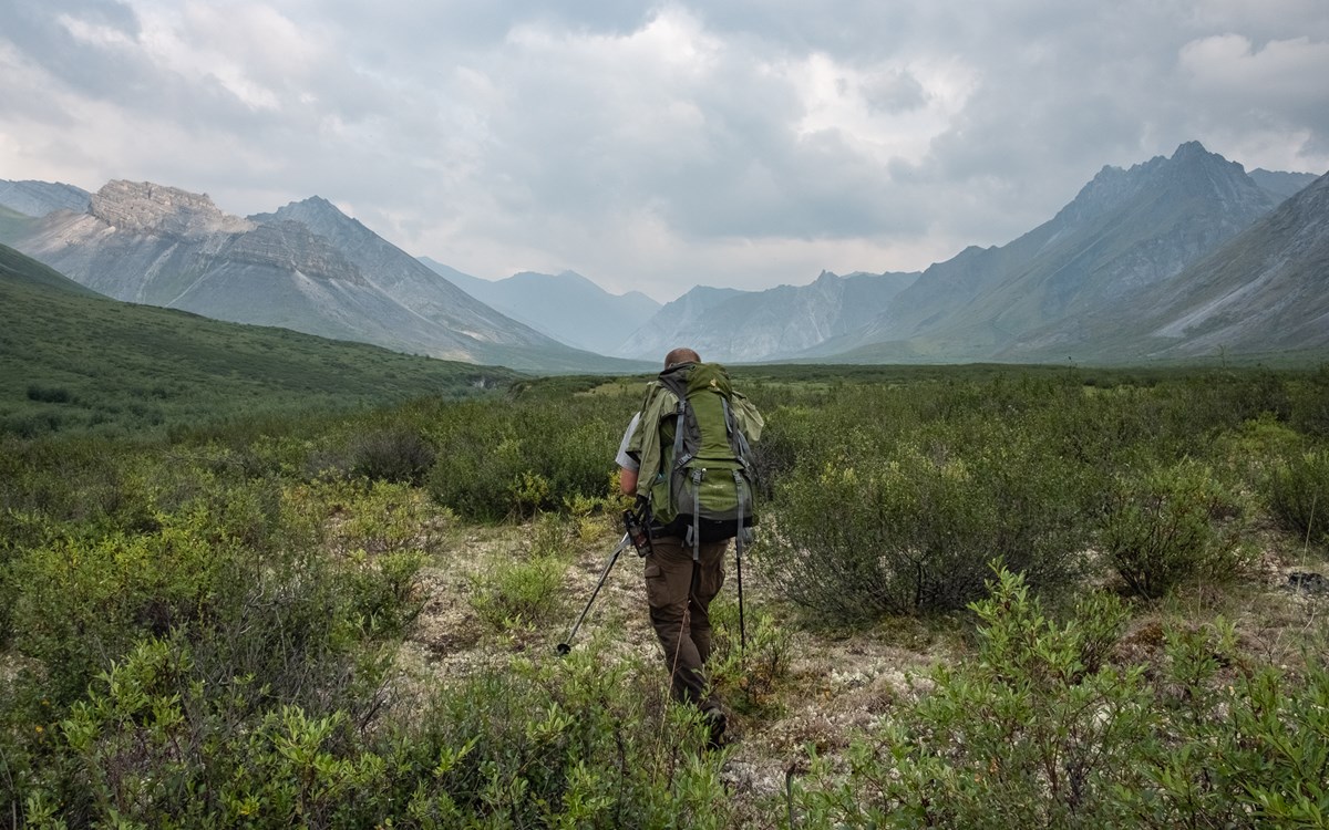 A Park Ranger backpacking through a mountain valley