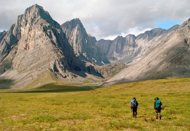 Two backpackers approach the majestic Hidden Valley in the Arrigetch Peaks area of the Brooks Range Two backpackers approach the majestic Hidden Valley in the Arrigetch Peaks area of the Brooks Range