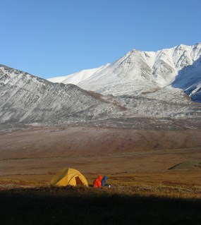 A tent and two campers on a sunny and cold day with a snowy mountain in the distance. A tent and two campers on a sunny and cold day with a snowy mountain in the distance.