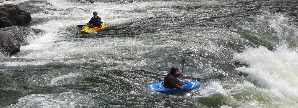 Two kayakers approach big whitewater