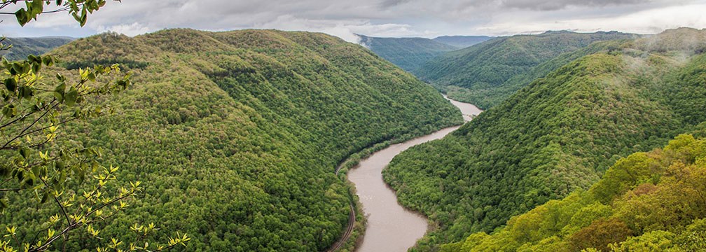 cloudy view of a river running through a deep, forested gorge