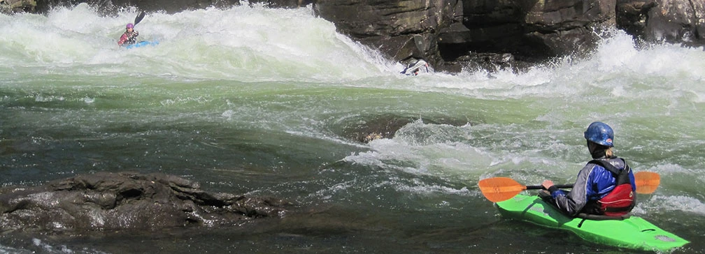 Kayaker watching a second kayaker navigate through rapids Kayaker watching a second kayaker navigate through rapids