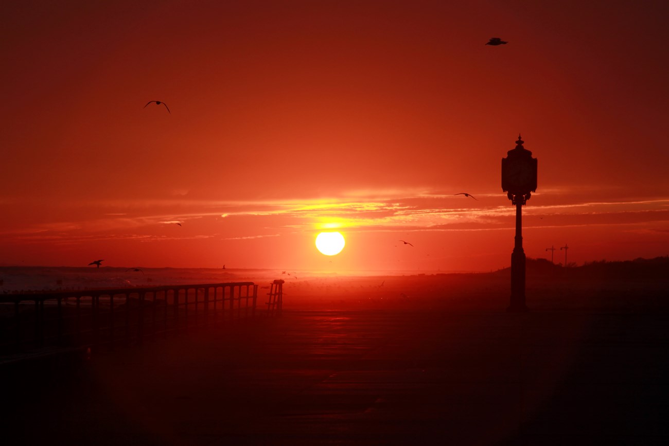 Sunset over the beach with silhouette of clock