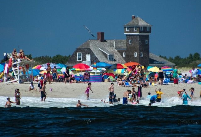 Visitors enjoy the beach on a summer day, with the former U.S. Life Saving Station in the background.  Photo by Volunteer-in-Parks Stan Kosinski.