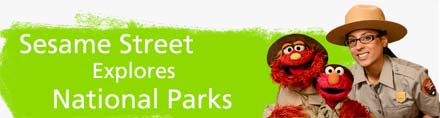 Elmo, Murray, and Ranger Shalini to the right of a green banner that reads - Sesame Street Explores National Parks. Elmo, Murray, and Ranger Shalini to the right of a green banner that reads - Sesame Street Explores National Parks.