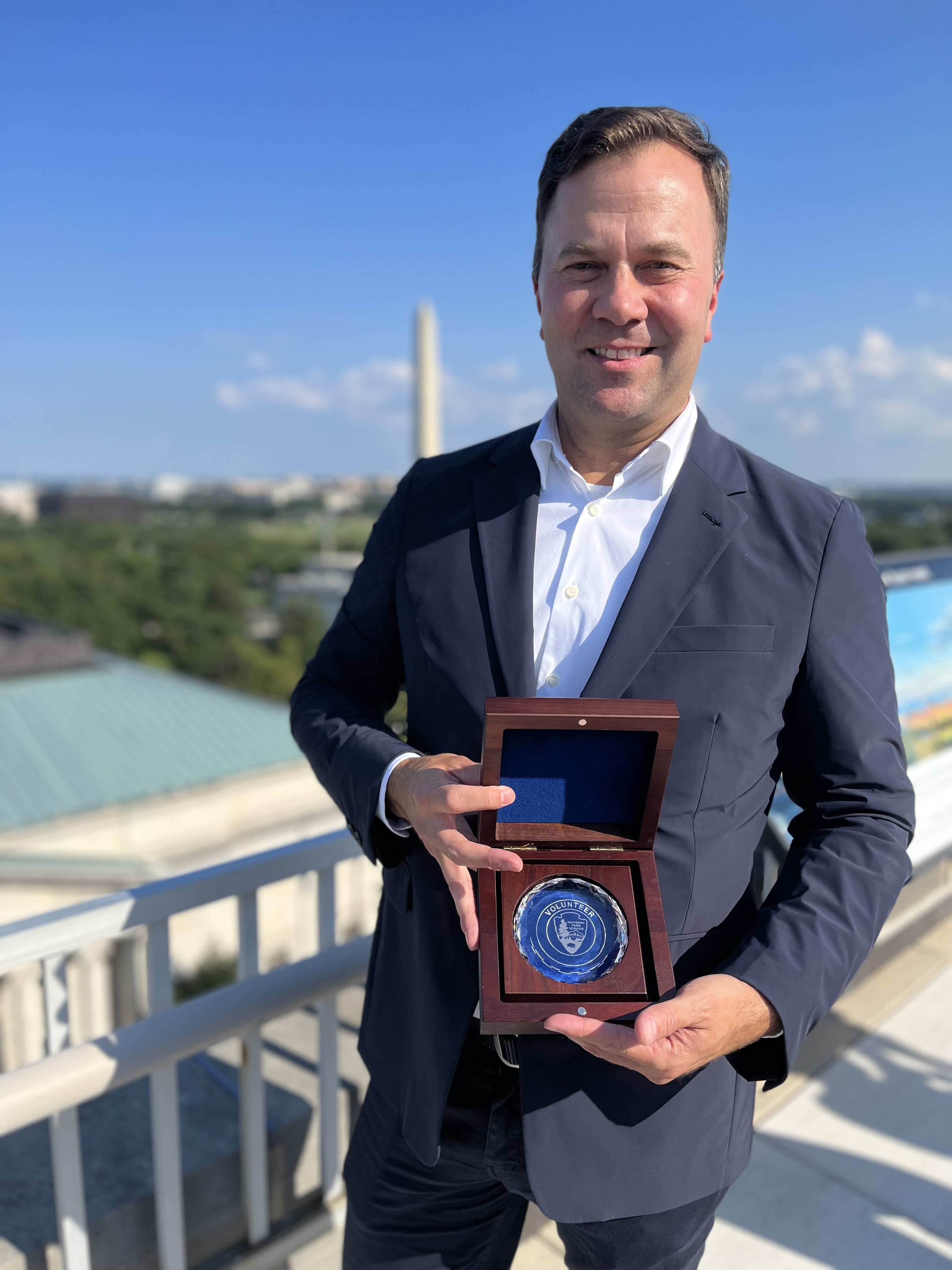 Chris Allieri and Hartzog award Man holding an award with Washington Monument in background