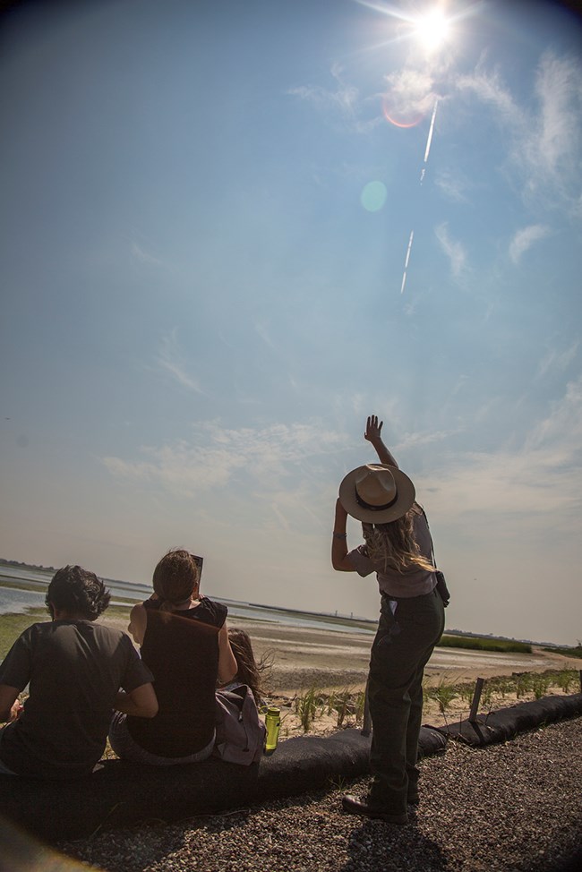 JBWR_ErinRangerPointsattheSun_21Aug2017_JWickersty Ranger Erin Schoppmeyer points at the sun during the 2017 solar eclipse at the Jamaica Bay Wildlife Refuge