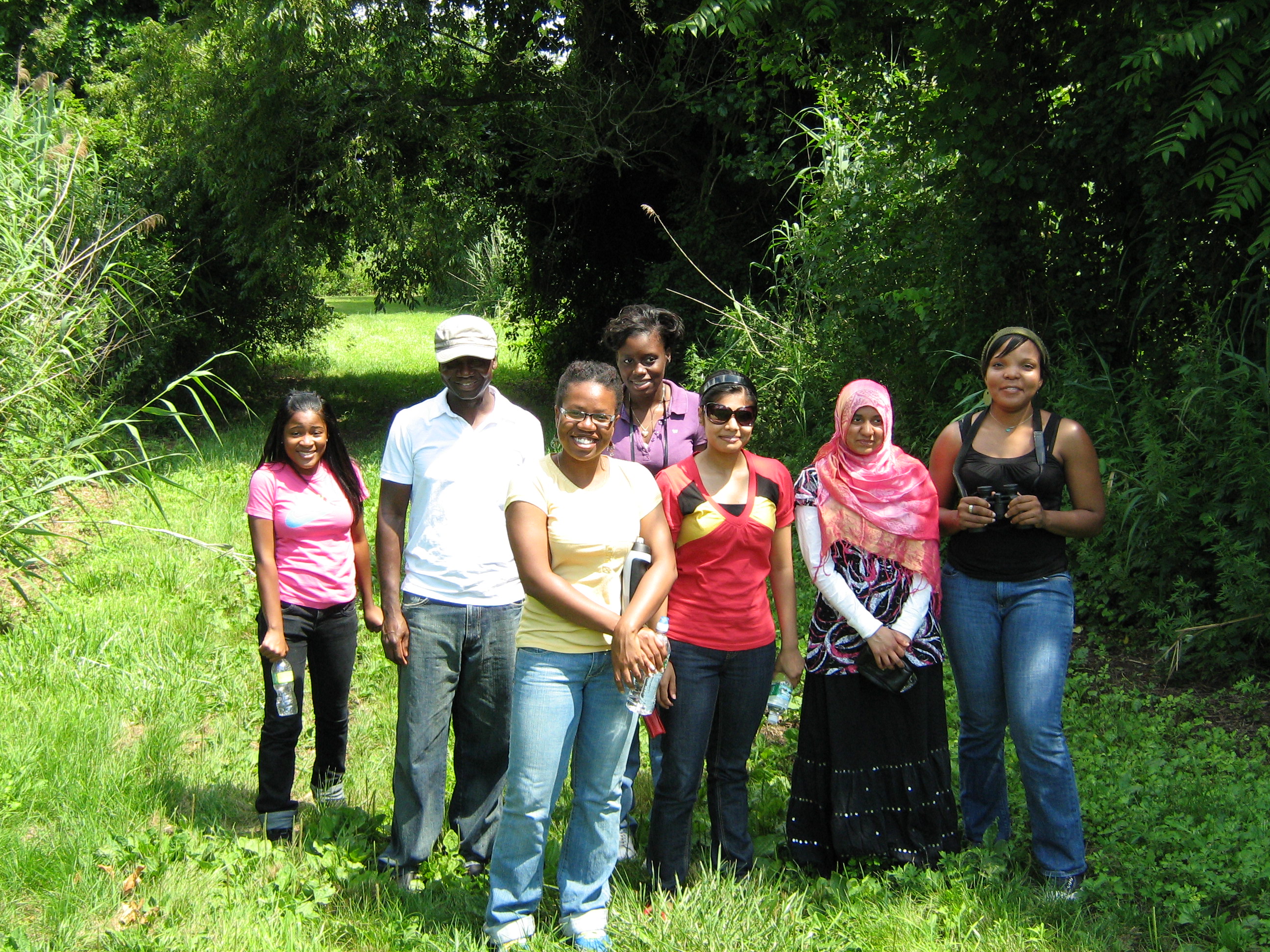 Interns with filmmaker Steve Ogumah hike through Floyd Bennett Field.