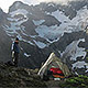 Hiker with tent nestled in some snowy peaks