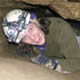 smiling female with protective gear emerging from cave