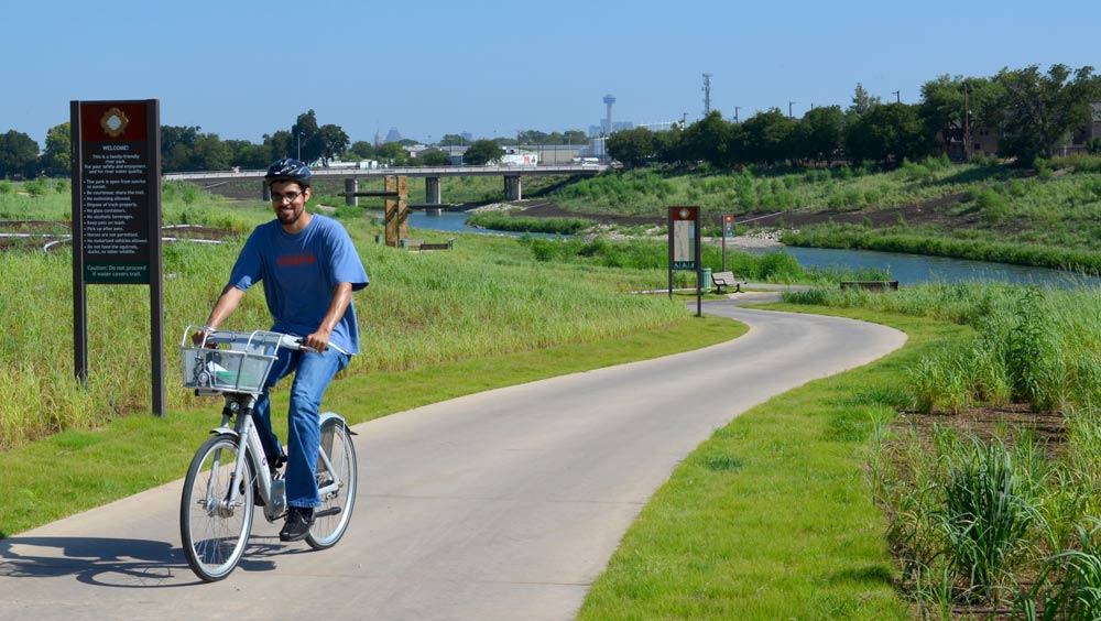 man riding a bicycle down a paved bike path man riding a bicycle down a paved bike path