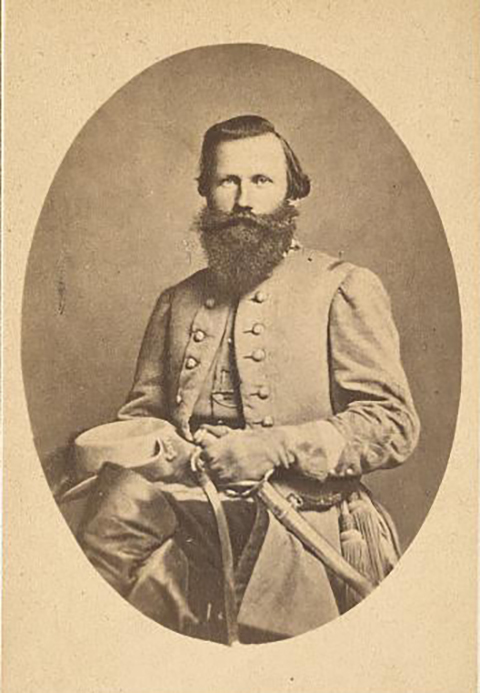  et svart-hvitt bilde av En Konføderert soldat som sitter i en stol. Han er iført sin fulle kjole uniform og holder hatten og sabel i fanget. Han har langt skjegg og bart.