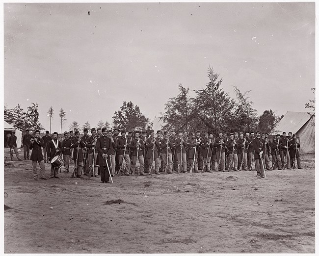 U.S. Civil War Soldiers stand in a line holding muskets