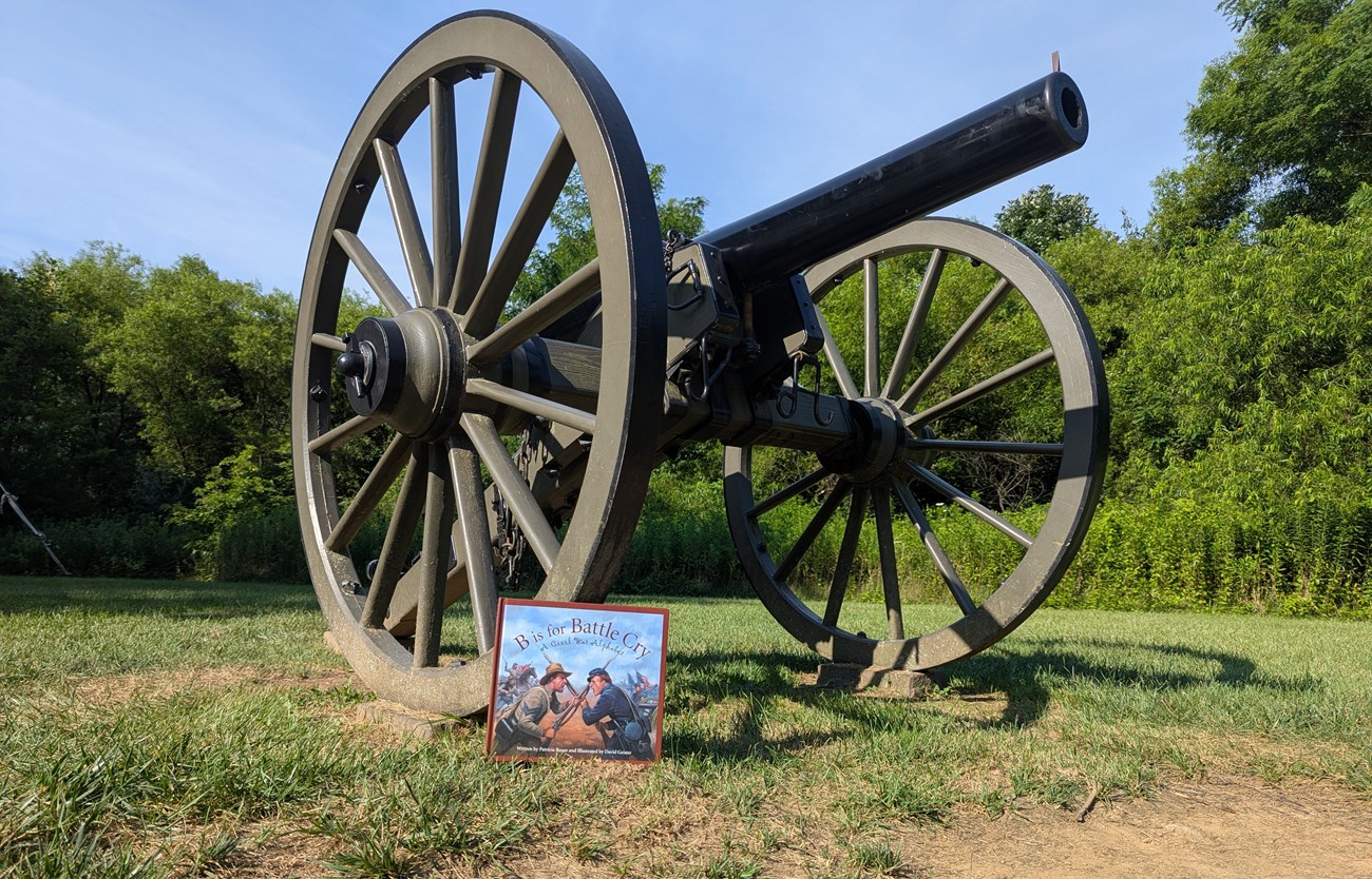 B is for Battlecry childrens book leaned against wheel of a cannon