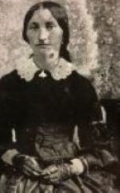 A woman wearing a black dress sits for a photograph.