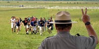 A Park Ranger watches children rush toward the Angle