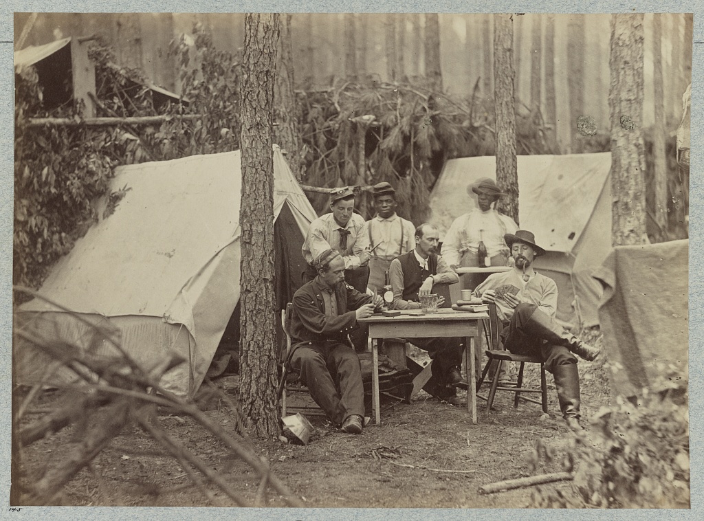 Officers of 114th Pennsylvania Infantry in front of Petersburg, Va., August, 1864; some sre playing cards at a table; one is smoking a pipe