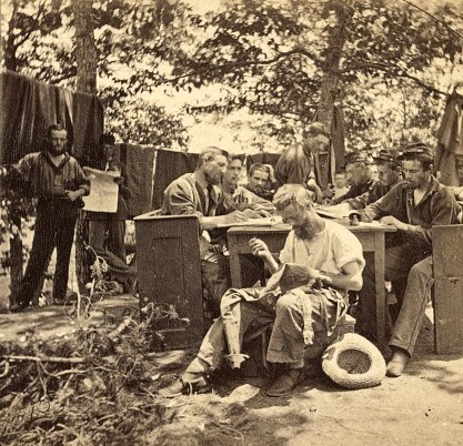 Civil War Soldiers In Camp A group of Civil War soldiers sit around a table in camp writing letters while another soldier sews his uniform