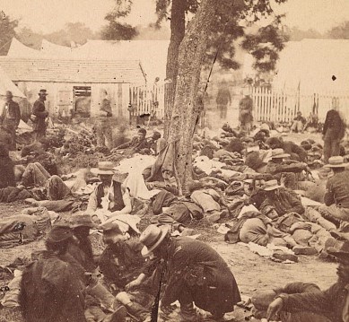 Civil War Field Hospital Scene Stereograph shows wounded soldiers awaiting examination at a field hospital at Savage Station, Virginia.