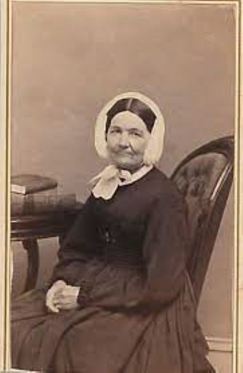Rosina Hubley sits for a photograph. She is wearing a black dress and white bonnett.