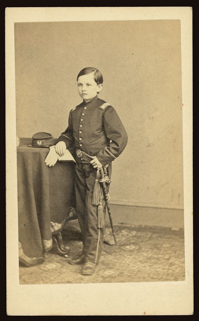 A young Tad Lincoln, wearing a Civil War soldier's uniform, poses for a photograph