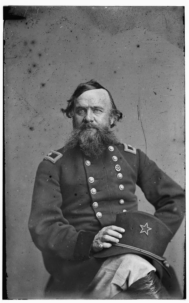 Photograph of a seated Brigadier General Alpheus Williams, holding his hat which features the star symbol of the 12th Army Corps.