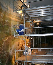 Workers delicately clean the surface of the cyclorama painting.
