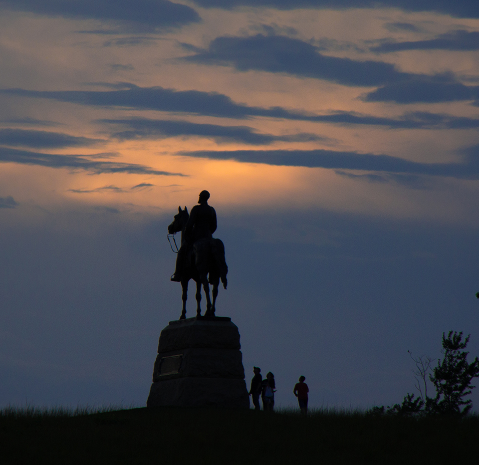 Visitors look up at the equestrian statue to Gen. George Meade at sunset.