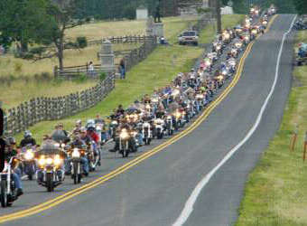 Hundreds of motorcycles drive along the Emmitsburg Road in the center of the Gettysburg battlefield.