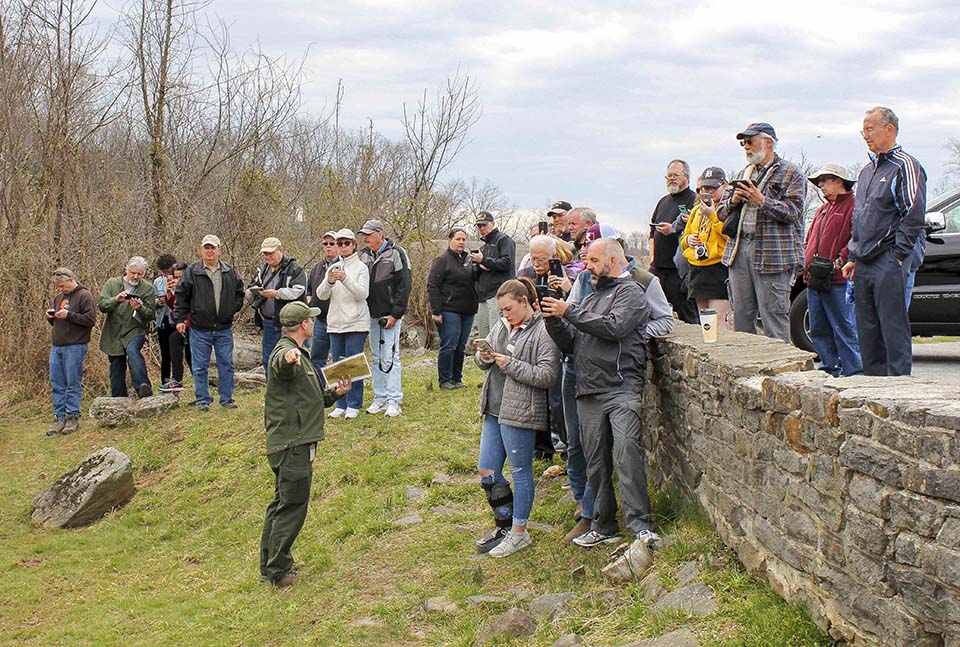A park ranger describes the location of a historic photo taken near Devil's Den in July, 1863 as visitors follow along via the Then and Now web page on their phones. A park ranger describes the location of a historic photo taken near Devil's Den in July, 1863 as visitors follow along via the Then and Now web page on their phones.