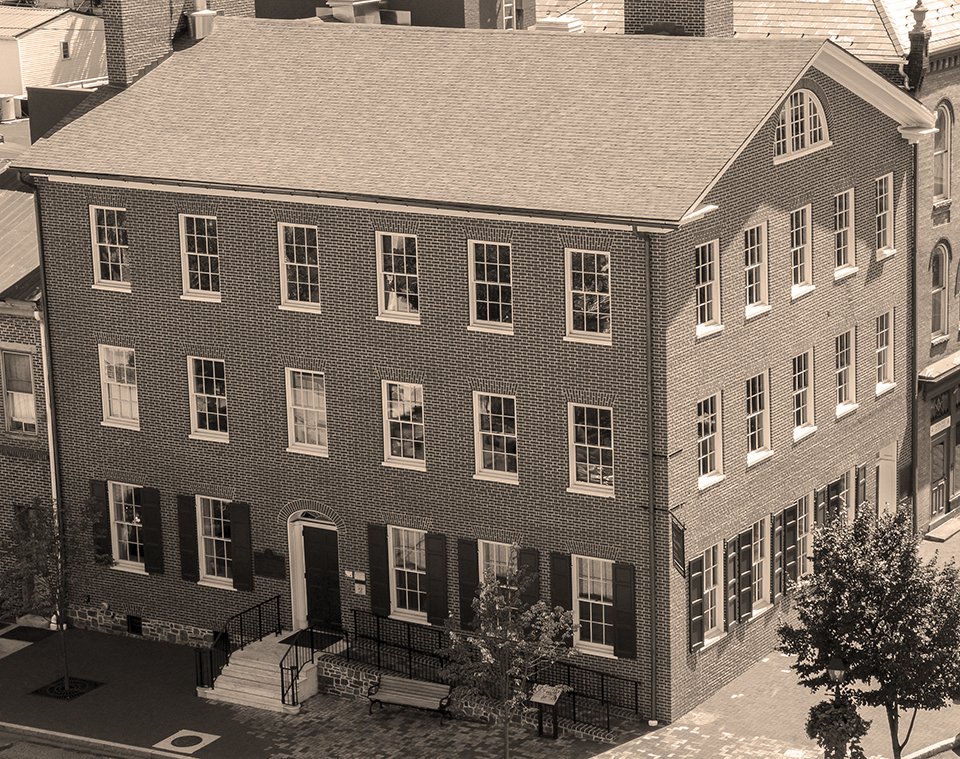 The David Wills house. A photograph of the Wills house in the center of Gettysburg. The building is a three story, red brick home but the photo has had a sepia tone filter applied to it.