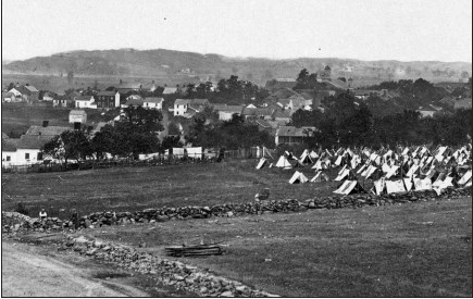 An 1863 detail of view northwest from Cemetery Hill that shows stone walls and a few dozen homes in the distance. This 1863 view of Gettysburg is looking northwest from Cemetery Hill. It shows a stone wall running along the left edge and another running from left to right. A few dozen homes are in the distance.