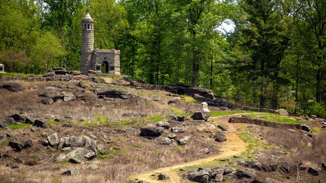A trail goes up a grass hill towards a castle looking monument
